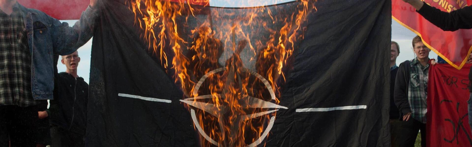 En bild på en samling ungdomar som bränner Natosflagga