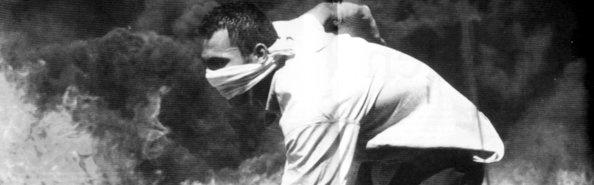 En man &auml;r i spr&aring;nget med brinnande fordon i bakgrunden