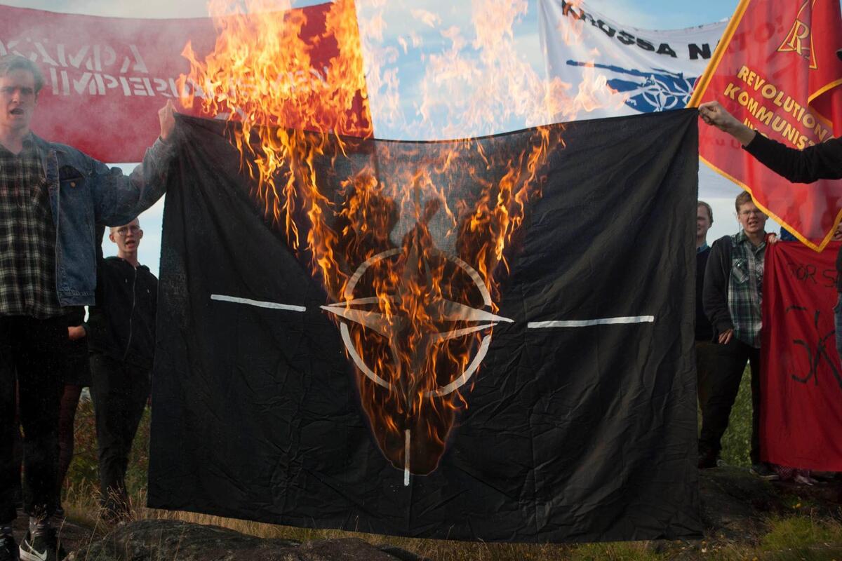 En bild på en samling ungdomar som bränner Natosflagga