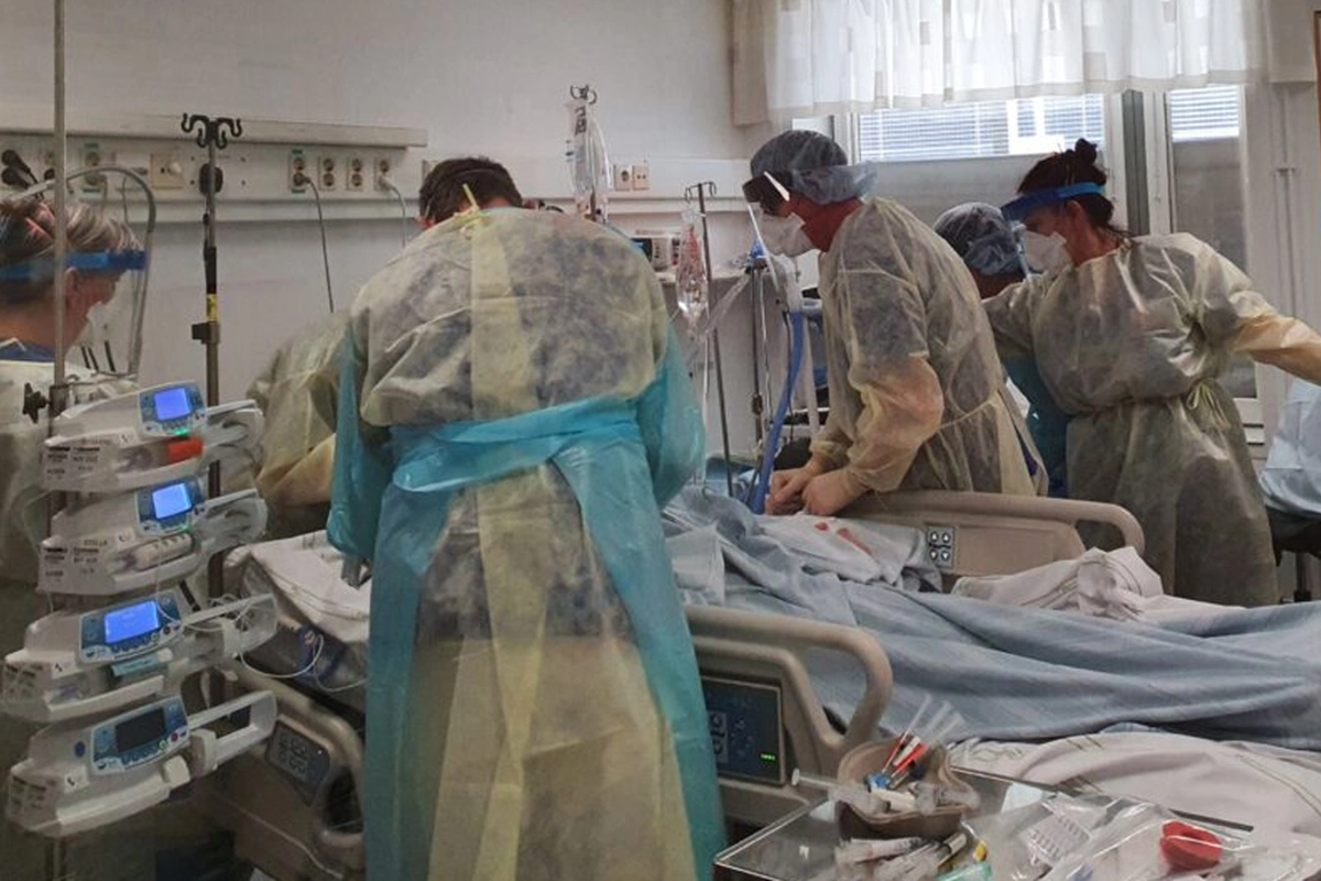 L&auml;kare i full mundering samlas kring en patient.