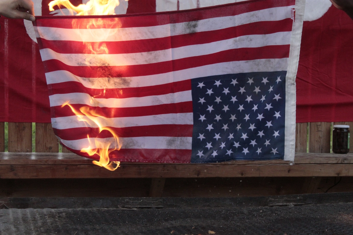 En USA flagga som h&auml;nger upp och ner brinner.